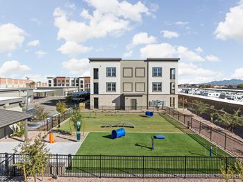 A park with grass and a playground in front of a building
